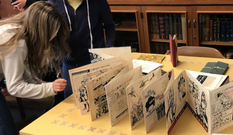 Students examine an old printed brochure from «Ӱҵ's special collection